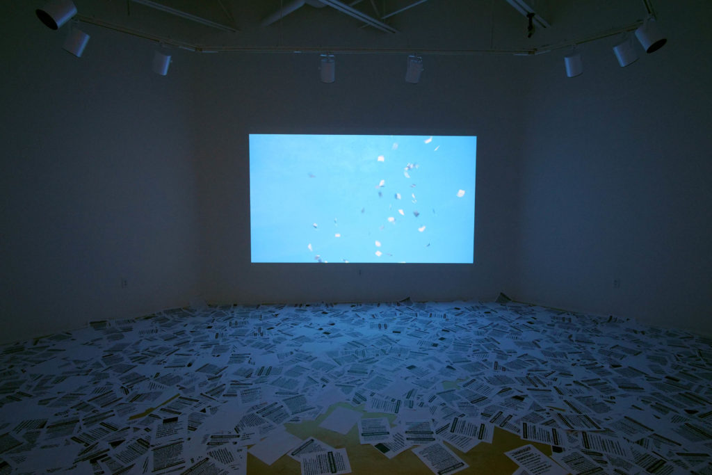 Oliver Ressler, “Fly Democracy”, video installation with leaflets, 2007 (Installation view: “Catastrophe Bonds”, Bush Art Center Galleries, St. Norbert College, De Pere, USA, 2018; photo: O. Ressler)